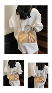 Detail view of the beige metallic ruched cloud bag with ring handles and slim shoulder strap