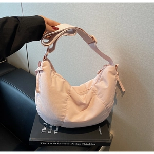 Detail of light pink nylon crescent bag with adjustable strap and side ribbon bows
