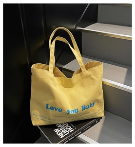 Detail of yellow canvas tote bag with Love You Baby blue print on a staircase