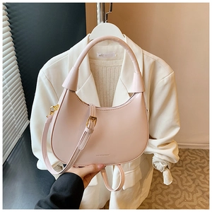 Close-up of minimalist light pink crescent handbag with adjustable strap and golden hardware