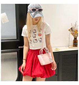 Detail of pink mini crossbody bag with heart pendant styled with a trendy casual outfit