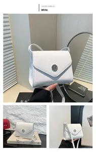 Détail du sac enveloppe en cuir verni blanc avec boucle métallique ronde en relief