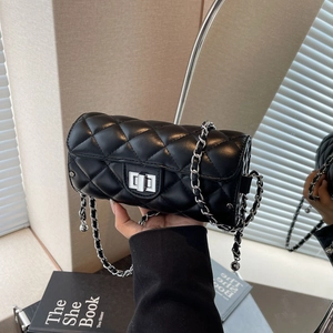 Détail du sac cylindrique noir matelassé avec bandoulière chaîne et fermoir argent
