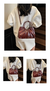 Detail view of burgundy pleated bucket bag with leather texture and matching shoulder strap