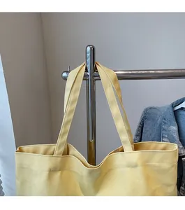 Close-up of the wide comfortable shoulder straps on a durable bright yellow canvas tote bag