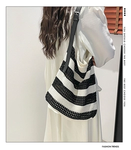 Detail of black and white striped hollow crochet tote bag with black leather shoulder strap