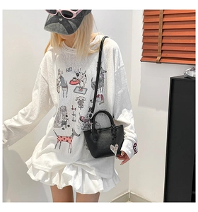 Close-up of black litchi grain leather bucket bag with heart charm and cartoon dog t-shirt