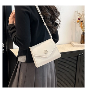 Vue détaillée d'un sac bandoulière en cuir verni blanc avec boucle ronde argentée