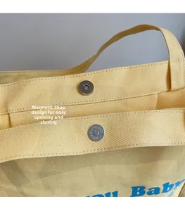 Close-up of secure magnetic closure on yellow canvas tote bag with textured fabric detail