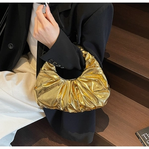 Detail of a metallic gold pleated hobo bag showing fine texture and crescent shape