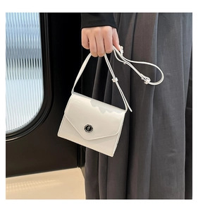 Détail d'un sac bandoulière en cuir verni blanc avec boucle métallique ronde lettre f