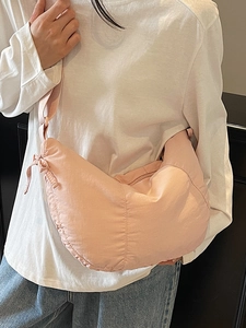 Pink crescent nylon tote bag with adjustable shoulder strap shown on a white shirt
