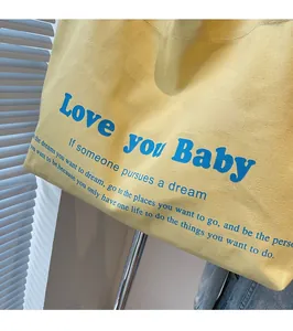 Detailed macro view of yellow canvas tote bag with blue artistic letter printing