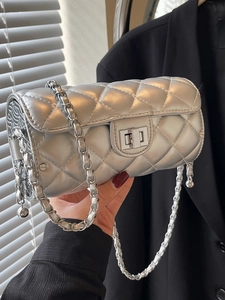 Sac cylindrique matelassé argenté avec chaîne et fermoir en métal porté par mannequin