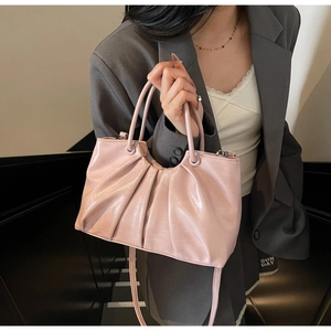 Close-up of pleated light pink oil wax leather handbag with glossy textured finish