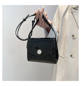 Détail d'un mini sac à rabat en cuir verni noir brillant avec un emblème f en métal argenté
