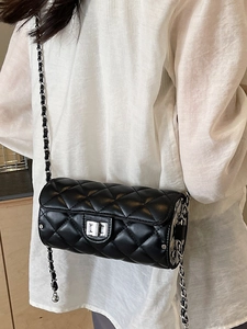 Sac cylindrique matelassé noir à chaîne porté en bandoulière par un mannequin
