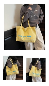 Detail showing high-capacity yellow canvas tote bag with Love you Baby blue print
