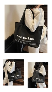 Detail of black canvas tote bag with Love you Baby print and long shoulder handles