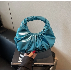 Close-up of metallic teal ruched handbag with glossy texture and crescent handle detail