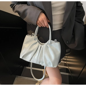 Detail of light blue wrinkled tote bag with dual handles and thin adjustable shoulder strap