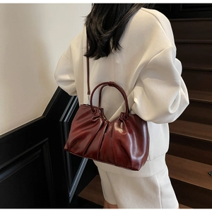 Detail view of burgundy pleated leather handbag with glossy oil wax finish