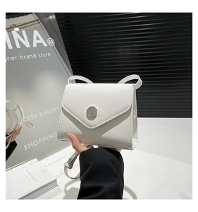 Détail du sac enveloppe en cuir verni blanc avec fermoir sceau métallique argenté