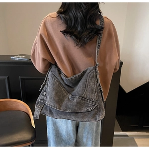 Detail of grey washed denim tote bag with multiple zipper pockets and wide shoulder strap