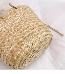 Close-up of woven straw bucket bag showing natural texture and drawstring closure details