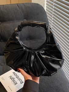 Minimalist black glossy pleated hobo bag for women in a stylish modern setting