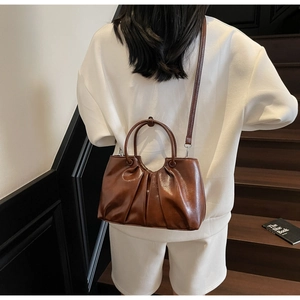 Brown oil wax leather handbag with pleats shown in a lifestyle scene on a staircase
