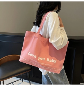 Detail view of large pink canvas tote bag with white quote worn on the shoulder