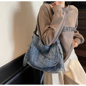 Detail view of washed blue denim hobo bag featuring retro stitching and metal ring buckle