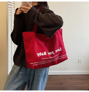 Close-up of a large red canvas tote bag with 'Love you Baby' printed text and durable straps