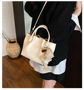 Detail of lychee textured leather bucket bag with cute plush dog pearl charm
