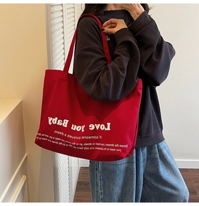Detail of red canvas tote bag featuring white Love you Baby typography print