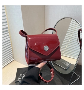 Détail du sac enveloppe en cuir verni rouge avec fermoir argenté et bandoulière