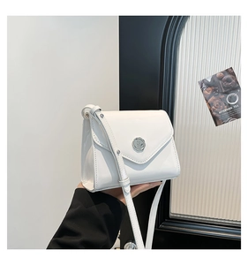 Détail d'un sac bandoulière en cuir verni blanc avec boucle argentée et rabat chic