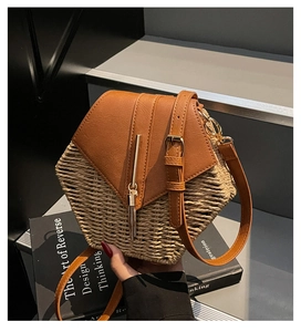 Detail of hexagonal straw crossbody bag with brown leather flap and golden tassel charm
