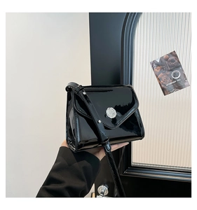 Détail d'un sac bandoulière en cuir verni noir brillant avec boucle en métal argenté