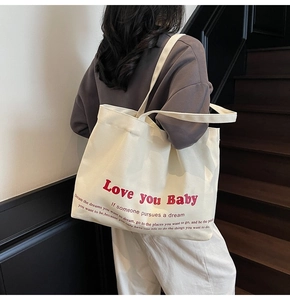 Detail of off-white canvas tote bag featuring bold red Love you Baby printed text