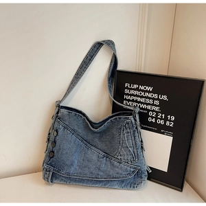 Detailed view of blue denim tote bag with vintage wash finish and metal button accents