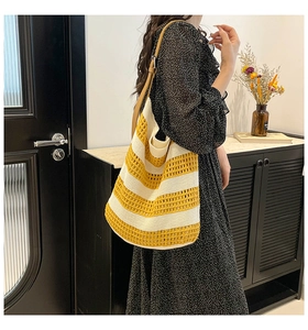 Detail of handwoven tote bag with yellow stripes and brown leather shoulder strap