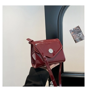 Détail du sac bandoulière en cuir verni bordeaux avec boucle en métal argenté ronde