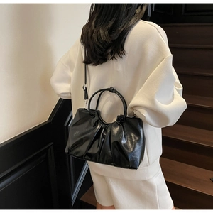 Detailed back view of a black glossy pleated crossbody bag with a round handle