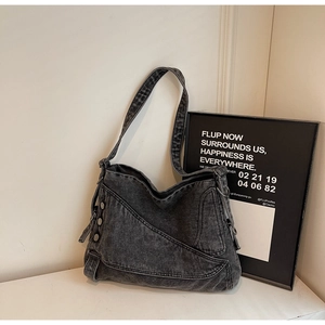 Detail of dark denim tote bag featuring metallic rivets and asymmetrical stitching