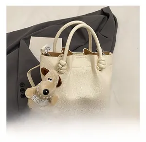 Detail shot of white lychee texture bucket bag with puppy charm and crossbody strap