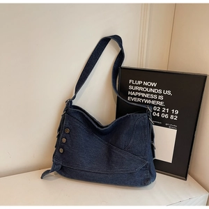 Detailed view of dark blue denim tote bag with vintage silver metal buttons and wide strap