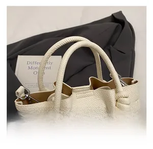 Detailed close-up of cream lychee leather bucket bag with woven handle and plush charm