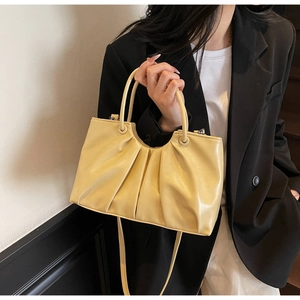 Detailed view of cream pleated handbag with slim handles and oil-wax leather texture